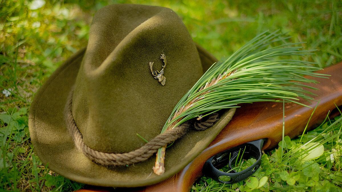 Ein Jägerhut und ein Gewehr, die auf Moos liegen. © Lukas - stock.adobe.com