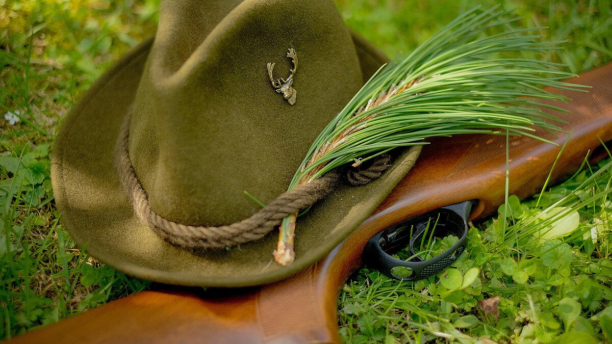 Ein Jägerhut und ein Gewehr, die auf Moos liegen. © Lukas - stock.adobe.com