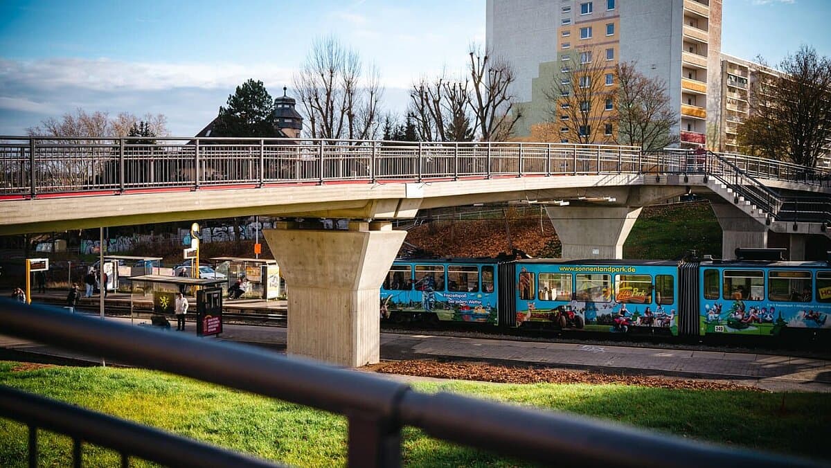 Eine Brücke, unter der eine Straßenbahn durchfährt. © TMDI/ Tony Matysik