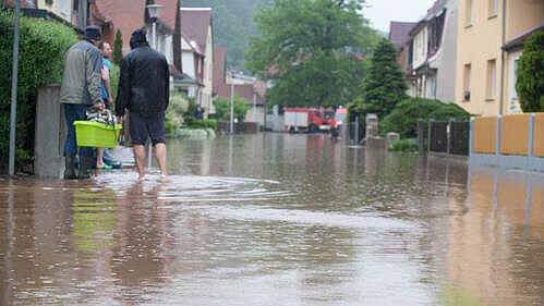 3 Personen auf der überfluteten Straße im Hochwasser