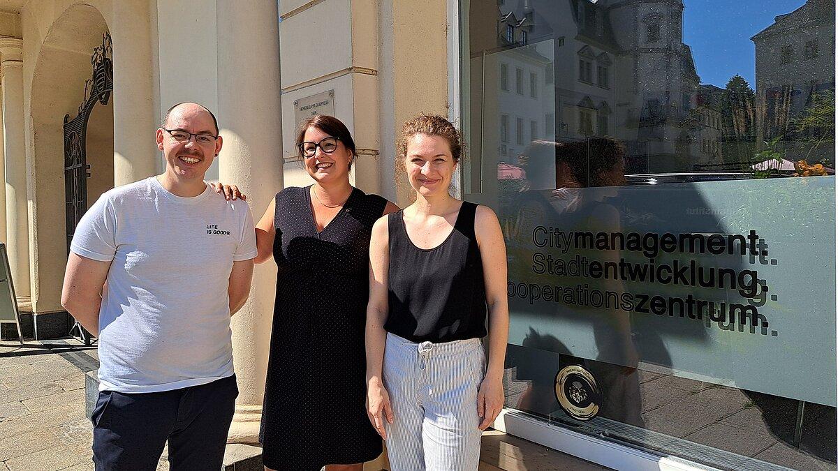 Zwei Frauen und ein Mann, die vor einem Bürofenster auf dem Markt stehen. © Stadt Gera