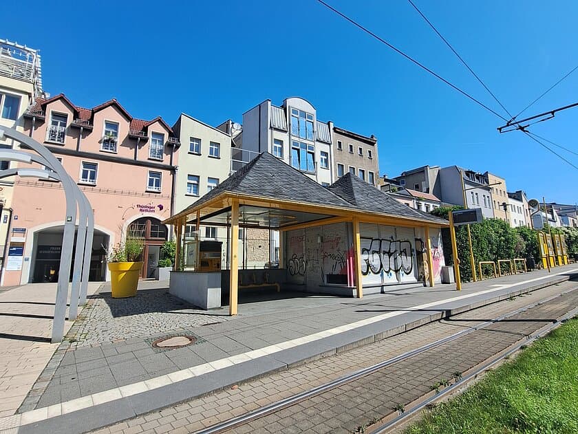 Eine Straßenbahnhaltestelle mit einem kleinen Häuschen, die Fronten sind mit Grafitti beschmiert. © Stadt Gera