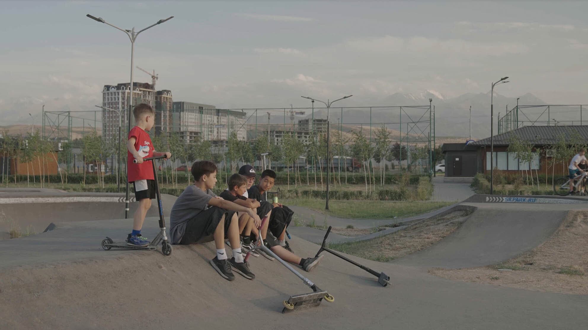 fünf Jungs, teilweise mit Roller, befinden sich zusammen auf einem Skatepark. © ©Finn Weigt