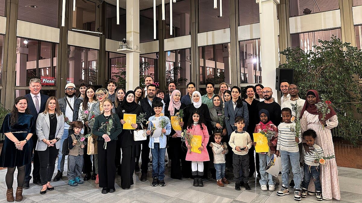 Etwa 50 Männer, Frauen und Kinder aus unterschiedlichen Kulturen stehen als Gruppe zusammen und blicken in die Kamera.. © Stadt Gera