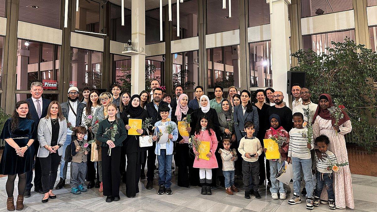 Etwa 50 Männer, Frauen und Kinder aus unterschiedlichen Kulturen stehen als Gruppe zusammen und blicken in die Kamera.. © Stadt Gera