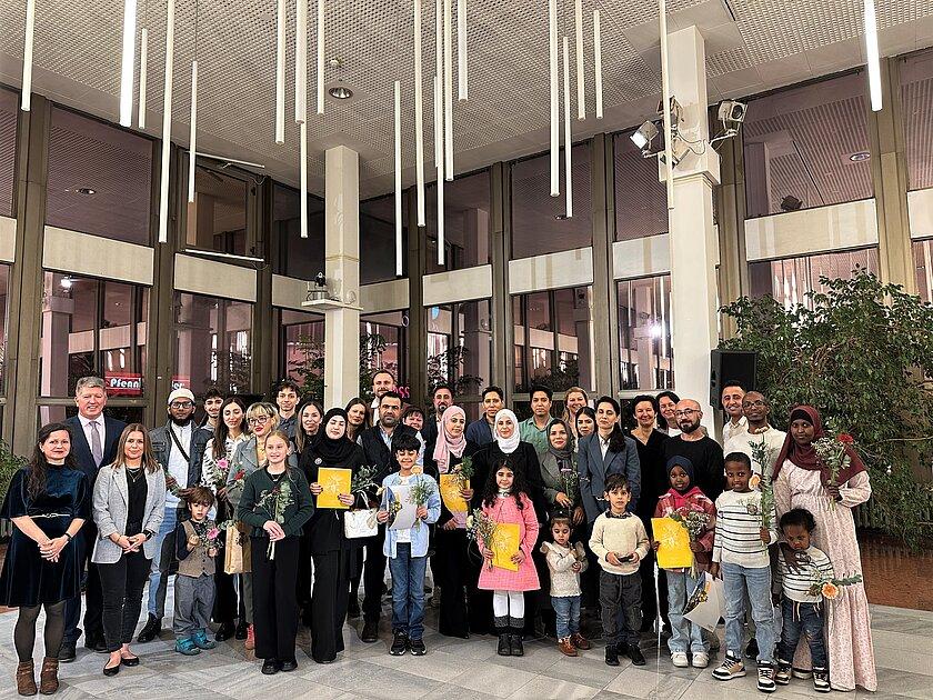 Etwa 50 Männer, Frauen und Kinder aus unterschiedlichen Kulturen stehen als Gruppe zusammen und blicken in die Kamera.. © Stadt Gera