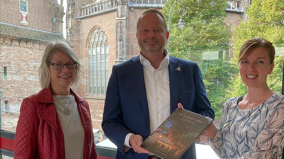 Steffi Koop und Christina Martens übergeben Buch mit Fotos aus Gera an den Beigeordneten des Bürgermeisters von Arnheim, Maurits van de Geijn.