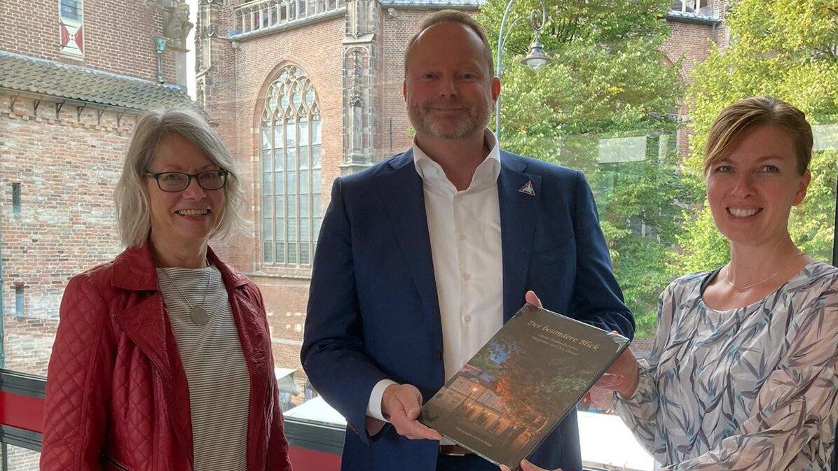 Steffi Koop und Christina Martens übergeben Buch mit Fotos aus Gera an den Beigeordneten des Bürgermeisters von Arnheim, Maurits van de Geijn.