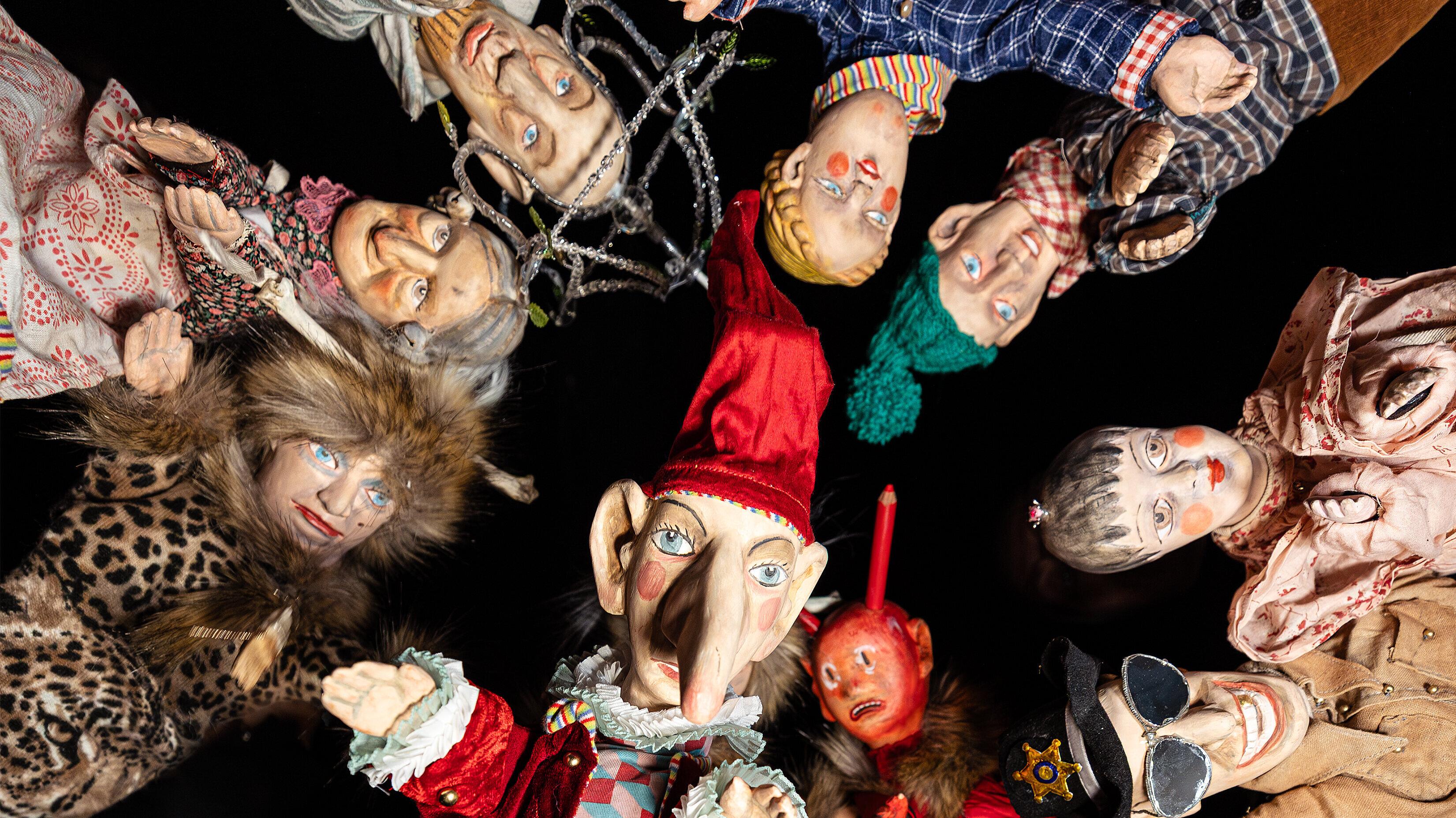 Eine Gruppe von Puppen schaut vor einem schwarzem Hintergrund in die Kamera. © Theater Gera Altenburg