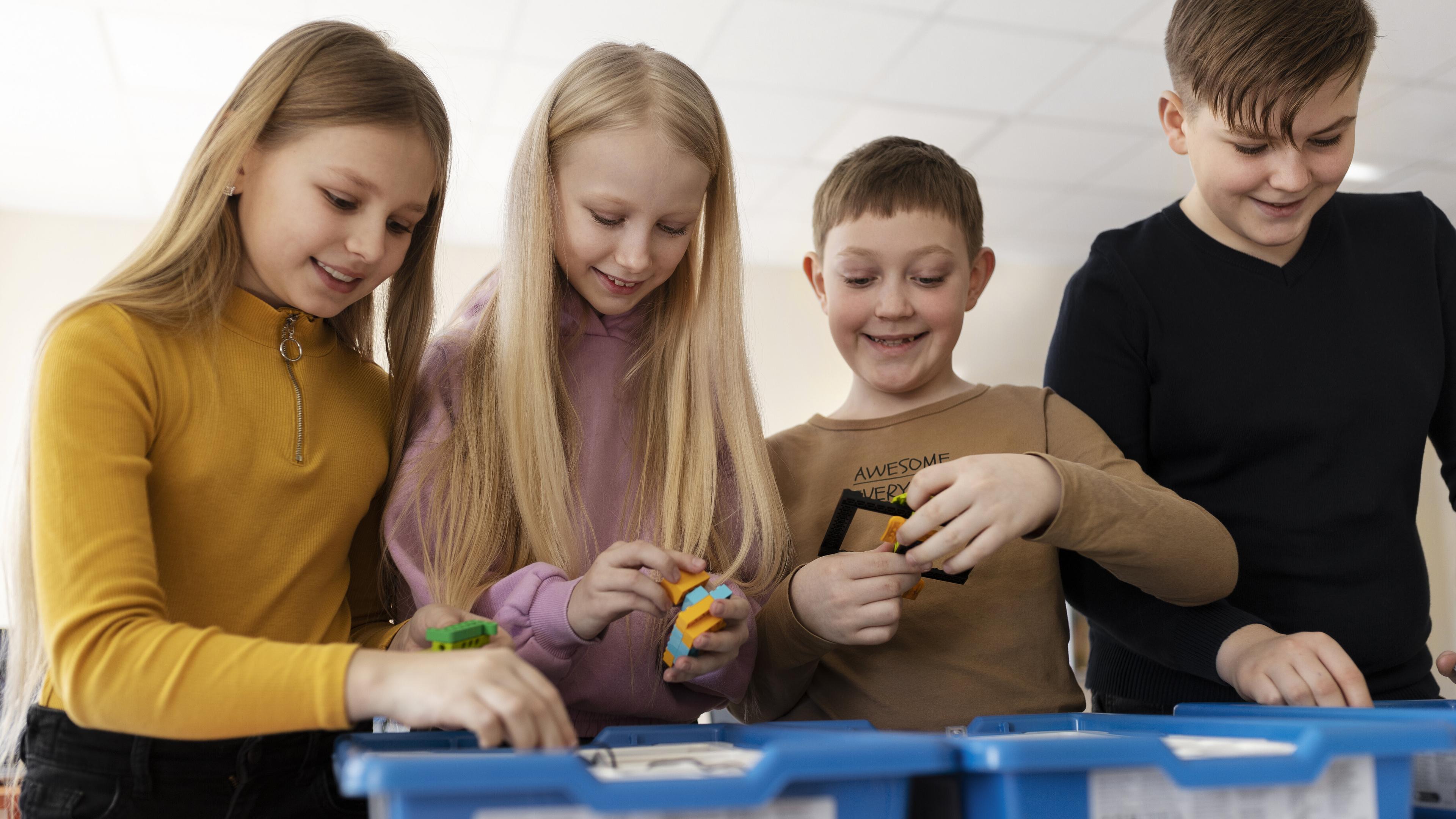 Vier Kinder bauen und programmieren mit Lego Spike.. © Freepik